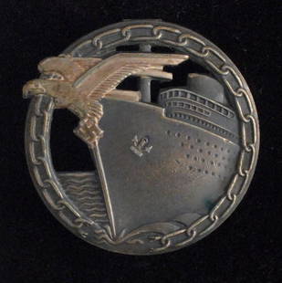 Kriegsmarine Blockade Breakers Badge (silver and grey).: An approaching grey coloured Merchant ship at sea with a silver eagle and swastika on the bow breaking a circular silver binding chain. Maker marked 'Fec. Otto Placzek Berlin Ausf. Schwerin Berlin' wi