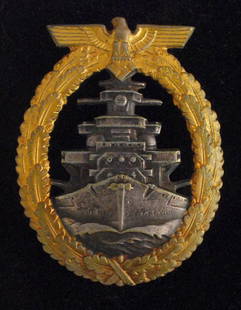 Kriegsmarine High Seas Fleet Badge (gilt and grey).: A grey approaching battleship within a gilt oval oak-leaf wreath surmounted by an eagle and swastika. Maker marked 'Fec. Adolf Bock Ausf. Schwerin Berlin' with a vertical broad flat pin and catch. A g