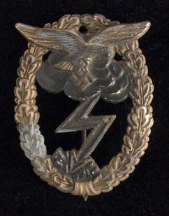 Luftwaffe Ground Combat Badge (silver and black).: A lightening bolt eminating from a black cloud and striking the ground within a silver oval oak-leaf wreath surmounted by an eagle and swastika. Non maker marked with a vertical pin and catch. A used