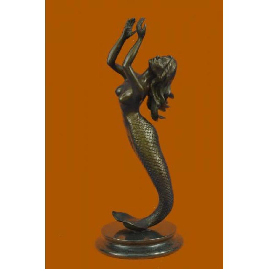 Signed Roche Mermaid Bronze Statue: The beautiful mermaid can be imagined, holding herself up with her fishtail, among the ocean's body of her water kingdom. Her arms are raised and cupped as her hair flows backwards taken by the moveme
