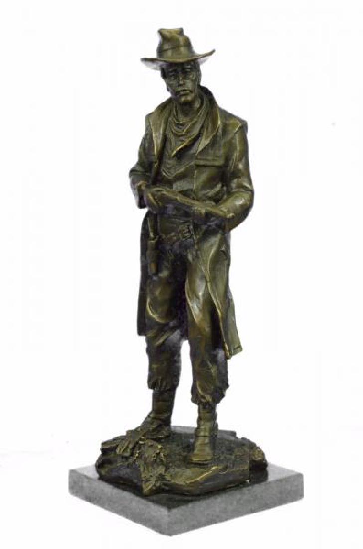Classic Cowboy With Gun Western Bronze Sculpture: This is a Sculpture of a classic cowboy. He wears his cowboy hat and his handkerchief loosely tied around his neck. His jacket is long and hangs to hiscalves and his gun hangs right below his waist li