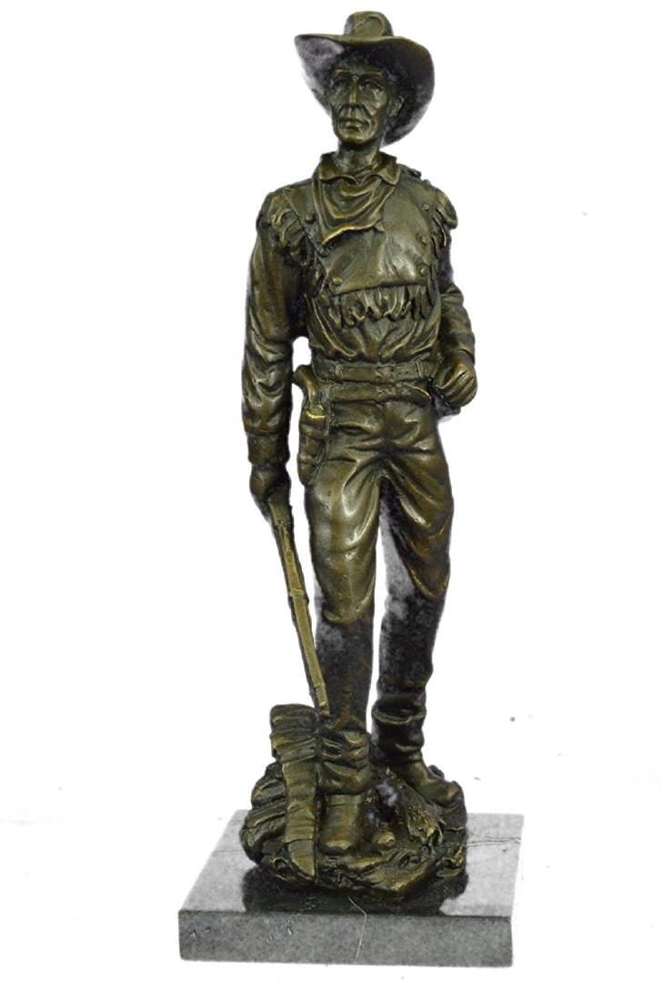 Cowboy Bronze Sculpture on Marble Base Statue: This is a Sculpture of a classic cowboy. He wears his cowboy hat and his handkerchief loosely tied around his neck. His jacket has hanging tassels and his gun hangs right below his waist line in his h