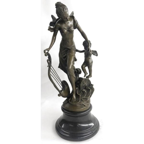 Fantasy Winged Fairy with Mythical Bronze Sculpture: A young cherub reaches to a fairy to gain her attention. The beautiful fairy reaches back to the cherub with a delicate to his playful curls. She\'92s holding a musical Harps in this enchanting sculpt