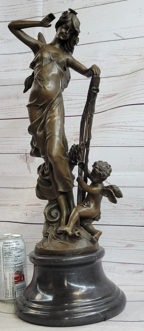 Butterfly Angel Nymph Fairy Bronze Sculpture: A young cherub reaches to a fairy to gain her attention. The beautiful fairy reaches back to the cherub with a delicate to his playful curls. She is holding a musical Harps in this enchanting sculptur