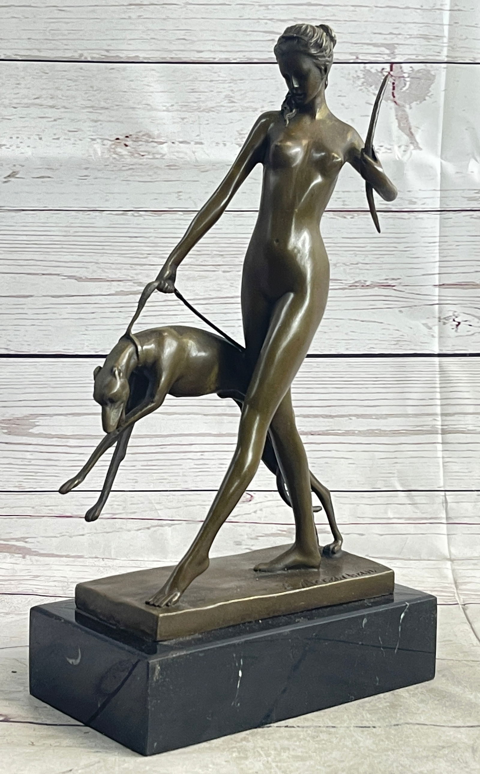 Diana the Hunter Bronze Sculpture: She poses with her small breasts exposed as she releases her bow. Her muscles and stomach as she leans back while unleashing her arrow. Standing on her toes she balances herself, bringing detail to he