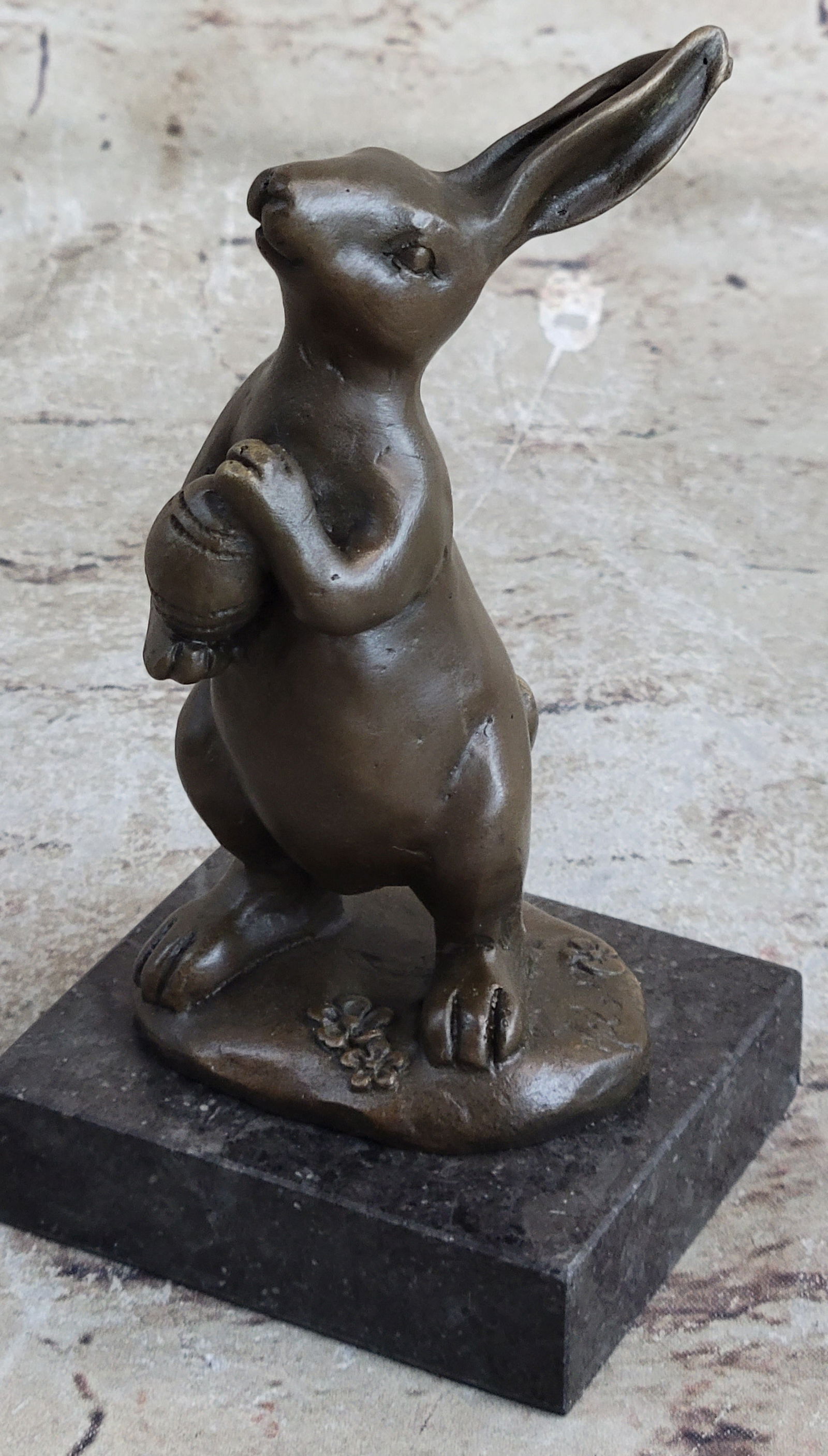 Mini Easter Bunny Bronze Sculpture: This cute and cuddly Lil lady looks up with the sweetest look and holds a tiny basket full of flowers in her tiny arms. This little bunny is the perfect touch of decor for a sweet and cute look. Her e