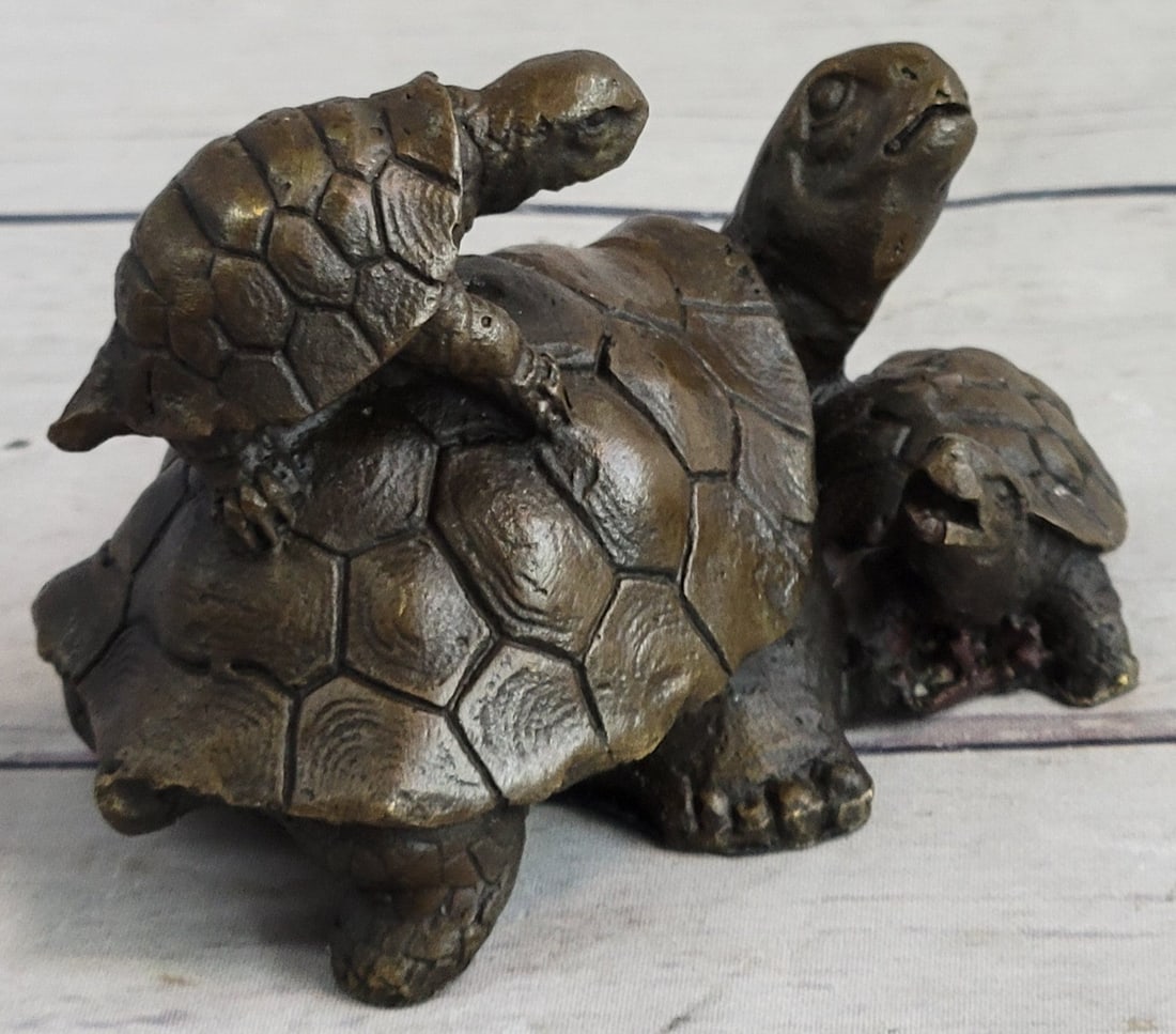 Turtle Bronze Sculpture: The turtle trio can be imagined clambering up each other\'92s backs trying to get to the best spot on a fallen tree to sun-bathe. The larger of the turtles situated in the middle try to look behind hi