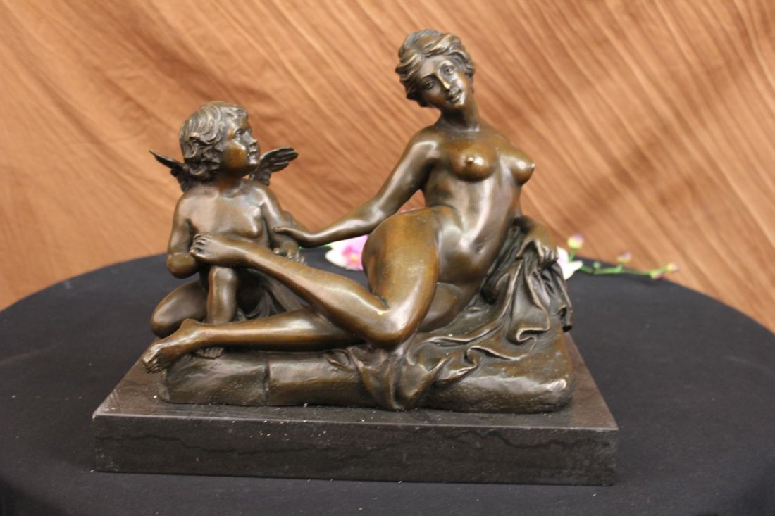 Cupid Comforting Aphrodite Bronze Sculpture After Louis: A Cherub And A Nude Woman Lay Playfully On A Long Seat. The Cherub Is Gazing Lovingly Towards The Woman. Her Nude Body Is Plump And Feminine Displaying Natural Curves. The Cherub Has Come Stand By Her