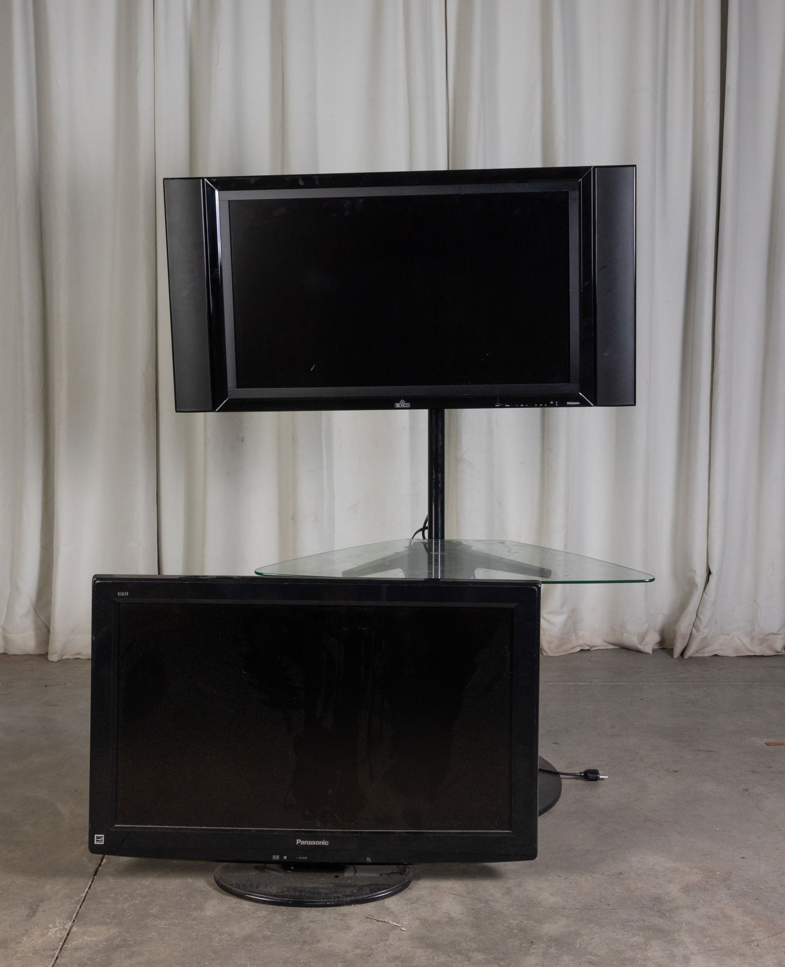 Two Flat Screen Televisions: Two Flat Screen Televisions: Panasonic LCD TV Model No. TC-L32U22 - Runco Crystal Series CR-32HD with base and attached glass table Literature Brooks Auction is not responsible for outbids. Questions