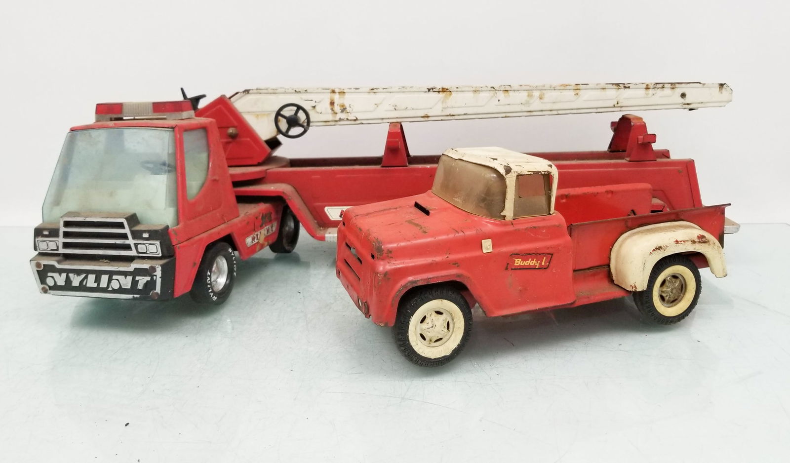 Two Vintage Metal Toy Trucks: Two Vintage Metal Toy Trucks: nylint aerial hook and ladder fire truck - Buddy L Red Vintage Pick Up Truck Size 6" x 8" x 30" Literature Brooks Auction is not responsible for outbids. Questions? Cal