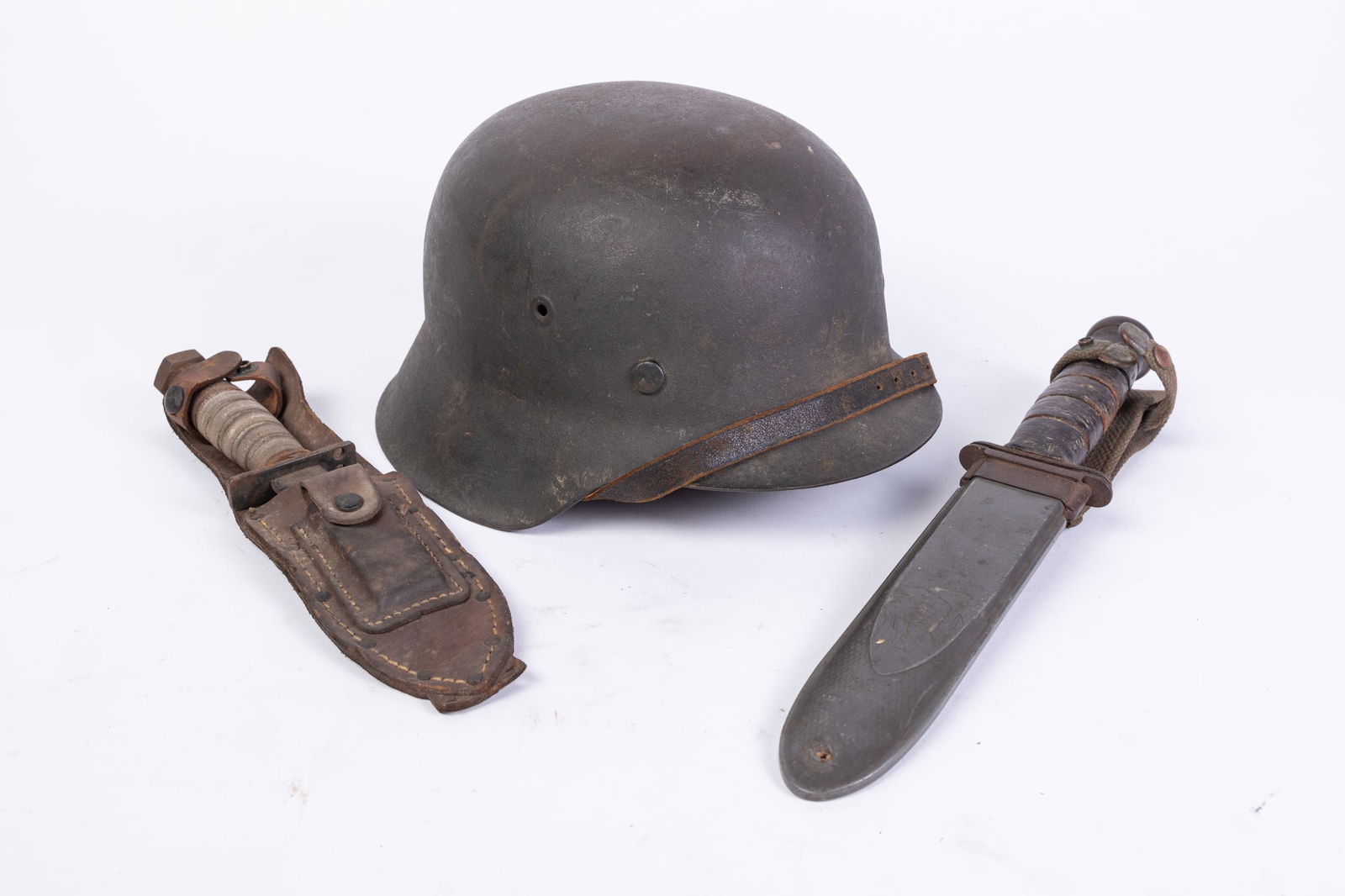 Three Pieces of Vintage Military Equipment: Three Pieces of Vintage Military Equipment: WWII USMC Mark 2 Fighting Knife - Vietnam era knife in sheath - metal vintage military helmet Size 7" x 12" x 12" Literature Brooks Auction is not responsi