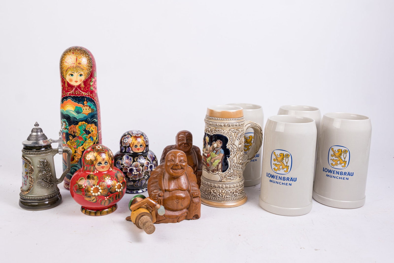 Assorted Souvenir Items: Assorted Souvenir Items: Lowenbrau stoneware mugs - Russian nesting dolls - carved wooden buddha figurine - and more Size 7" x 12" x 12" (box size) Literature Brooks Auction is not responsible for ou