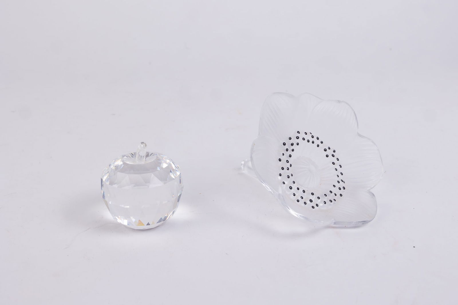 Lalique Anemone Paperweight & Swarovski Apple Paperweight: Lalique Anemone Paperweight & Swarovski Apple Paperweight: The lalique anemone has a chip on the underside of one of the petals Size 7" x 12" x 12" Literature Brooks Auction is not responsible for ou