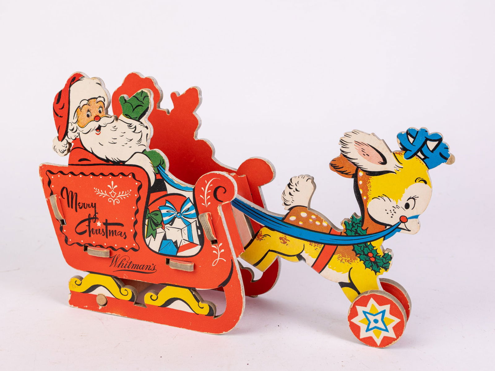 1950s Dolly Toy Co Whitman's Santa in Sleigh Toy: 1950s Dolly Toy Co Whitman's Santa in Sleigh Toy: A vintage, 1950s, hard pressed cardboard and wooden christmas toy advertising Whitman's chocolates. Features santa in sleigh with reindeer. Size 7" x