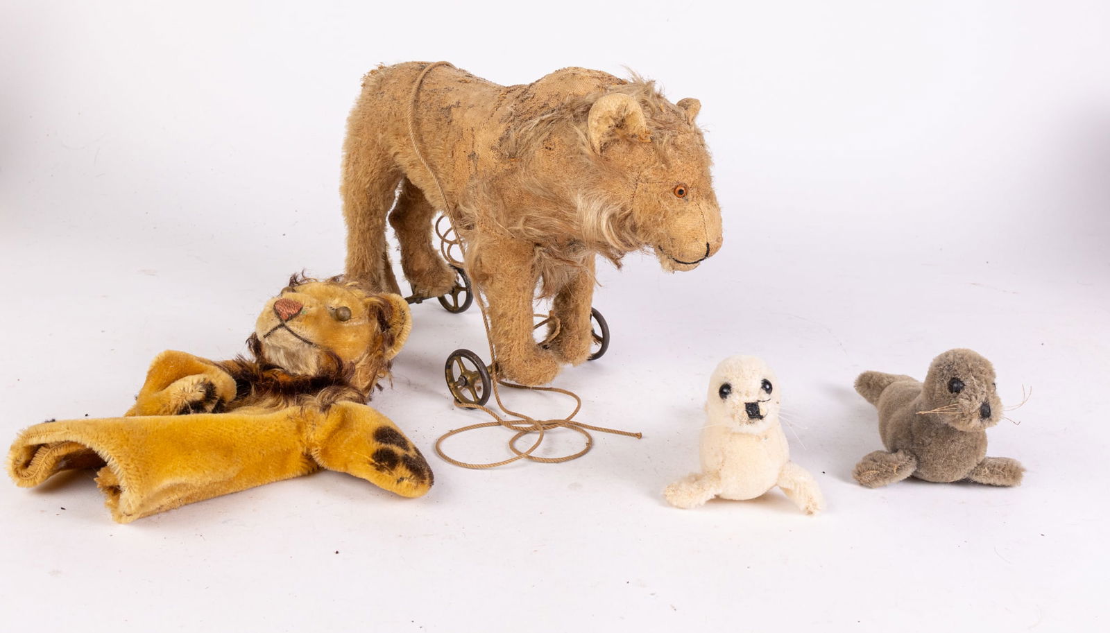 Antique Lion Pull Toy and Assorted Stuffed Animals: Antique Lion Pull Toy and Assorted Stuffed Animals: Antique Lion mohair pull toy - Steiff lion hand puppet - two Dakin vintage toy seals Size 9" x 11" x 4" Literature Brooks Auction is not responsibl