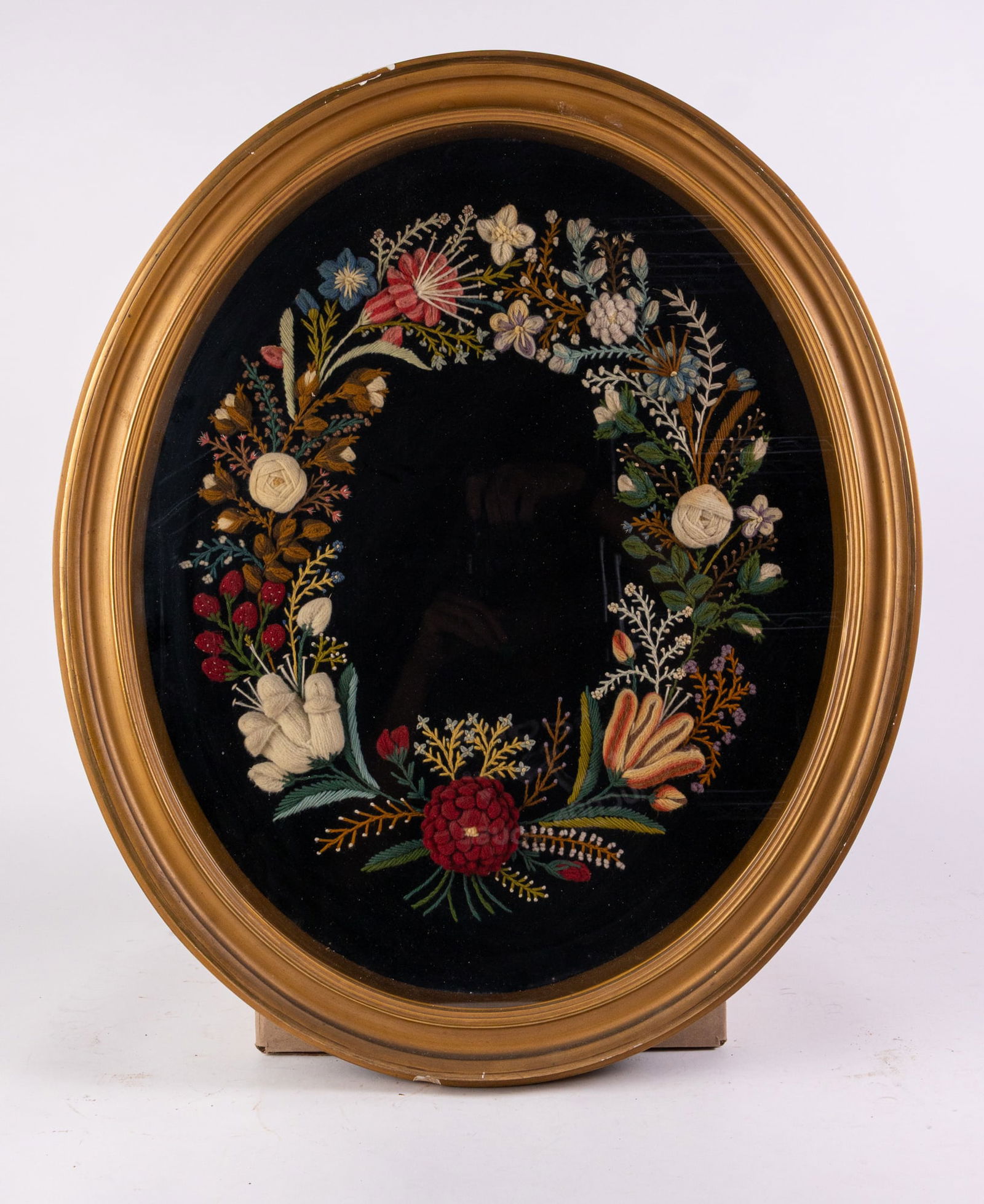 Intricate Floral Embroidery in Gold Toned Frame: Intricate Floral Embroidery in Gold Toned Frame, Finely embroidered floral wreath on black background in gold toned oval frame. Good condition. Size 25" x 21" x 2" Literature Brooks Auction is not re