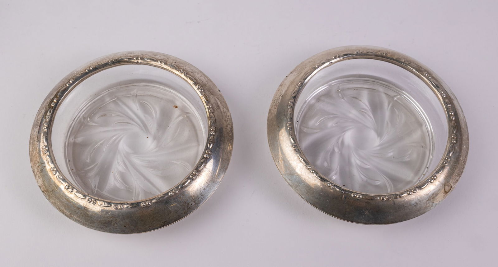 Two Sterling Silver Rimmed Coasters: (2) Sterling Silver Rimmed Coasters, marked Amston sterling 144 Literature Brooks Auction – Online Auction Terms & Conditions —————————̵