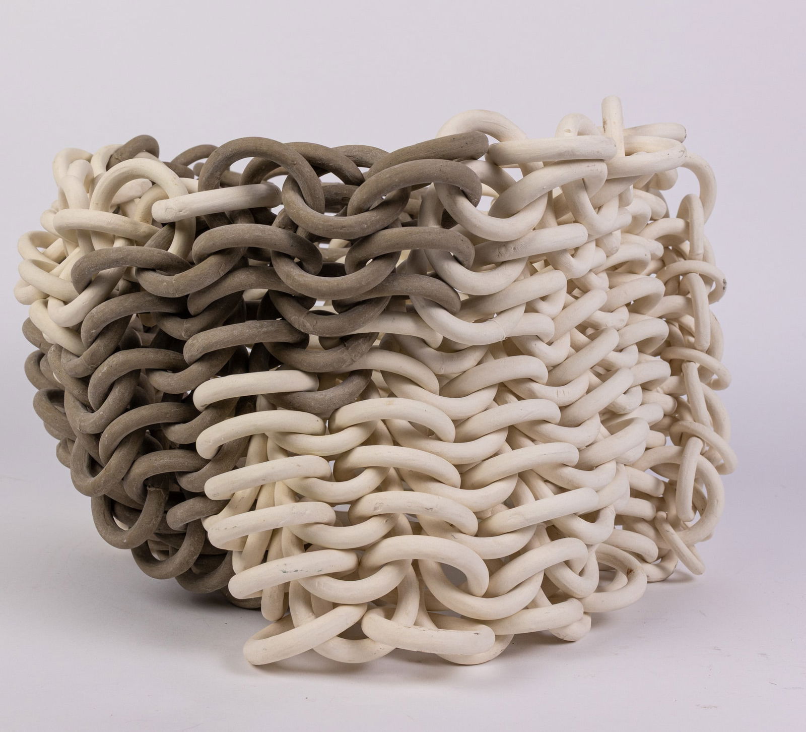 Ruth Borgenicht | "Seemed Cylinder" Chain Mail Bisque Stoneware Sculpture: This remarkable work is presented in outstanding condition. It features a series of intricately interwoven ceramic links, forming a chainmail-like composition that is both dynamic in movement and