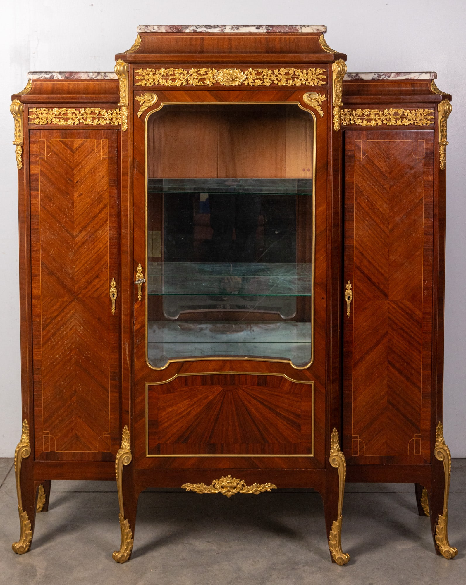 Antique Gilt French Vitrine: This luxurious piece features classic antique French design, including intricate gilt floral details, inlaid geometric woodwork, a marble top, dovetailed construction, and bevelled glass. On the