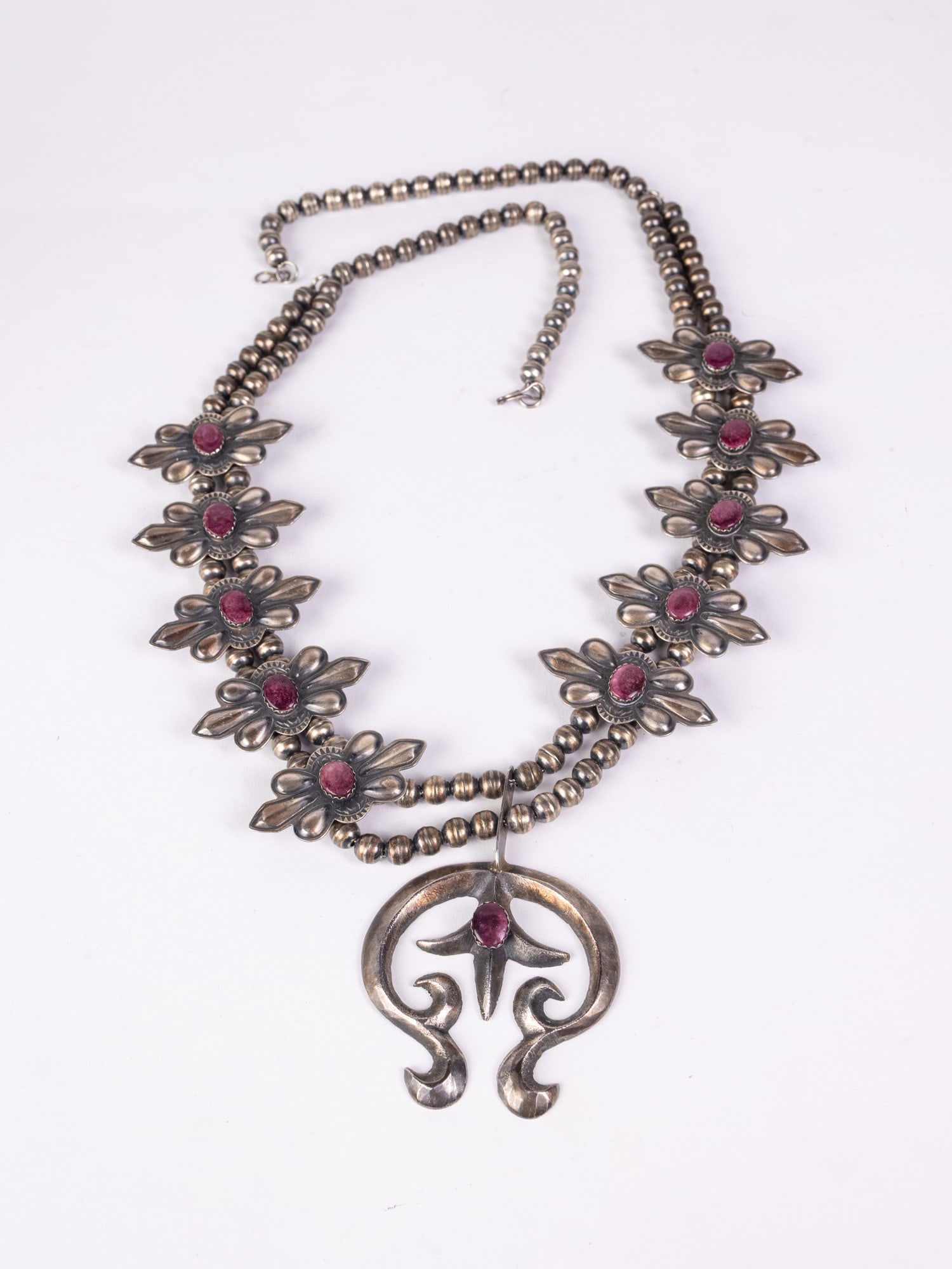 Native American Handcrafted Sterling "Squash Blossom" Necklace: Marked "RJ Sterling", total weight 95.1 grams. Decorated with purple stones, hook and eye claspLiteratureBrooks Auction – Online Auction Terms & Conditions Contact: (856) 694-2960 |