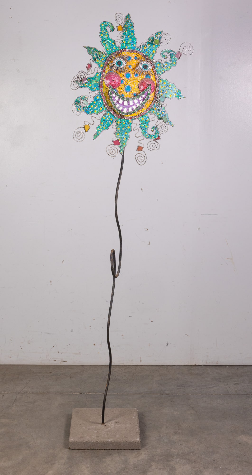 Unique Folk Art Psychedelic Sun Sculpture: Constructed from metal, concrete, mosaiced ceramic pieces, and an unforgettable smile, this mixed media sculpture has been crafted by an unknown artist. It stands around six feet tall and is mounted