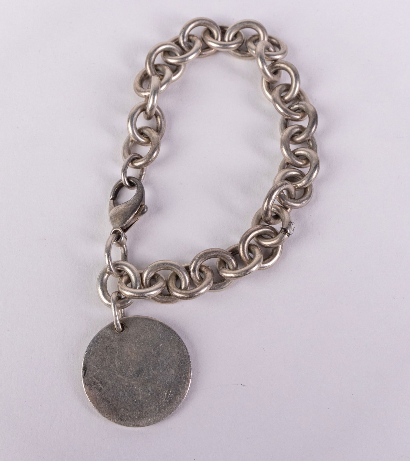 Tiffany & Co. | Round Tag Charm Bracelet: The "Return to" charm bracelet is a timeless piece in Tiffany's history, highlighting the brands commitment to simplistic elegance and quality materials. Marked "Tiffany & Co. 925", total