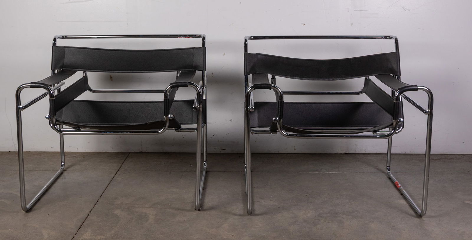 After Marcel Breuer | Pair of "Wassily" Chair Reproductions: originally designed by Marcel Breuer, the Wassily chair embodies the iconic Bauhaus aesthetic through clean, structural lines and minimalist form. Featuring tubular steel frames with sling-style leath