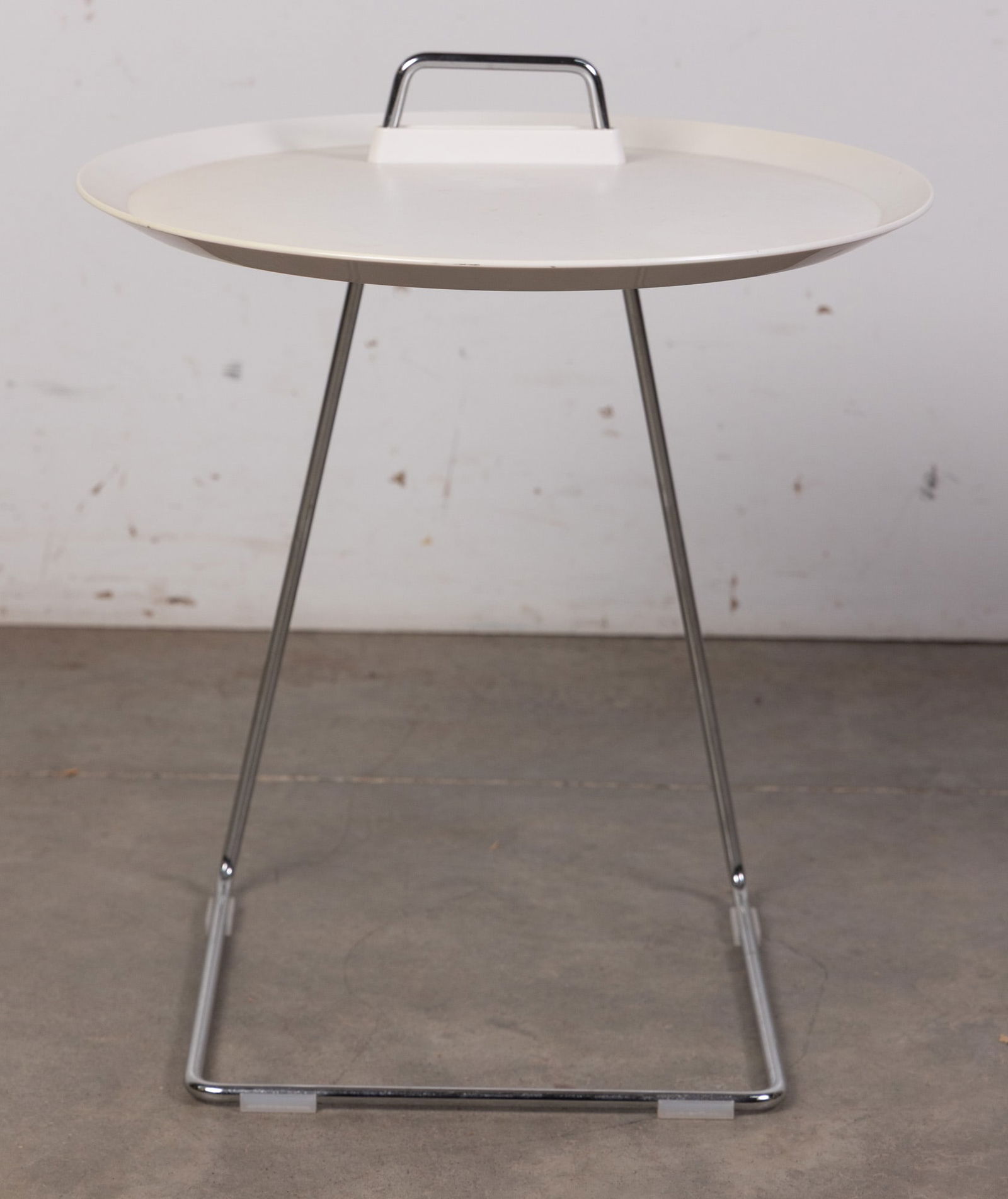 Speziell | Studio Domo Porter Side Table: a compact, multifunctional piece defined by its lightweight, industrial aesthetic. Featuring a slim chrome-plated wire frame and a removable plastic tray top, its clever C-shaped design allows it to