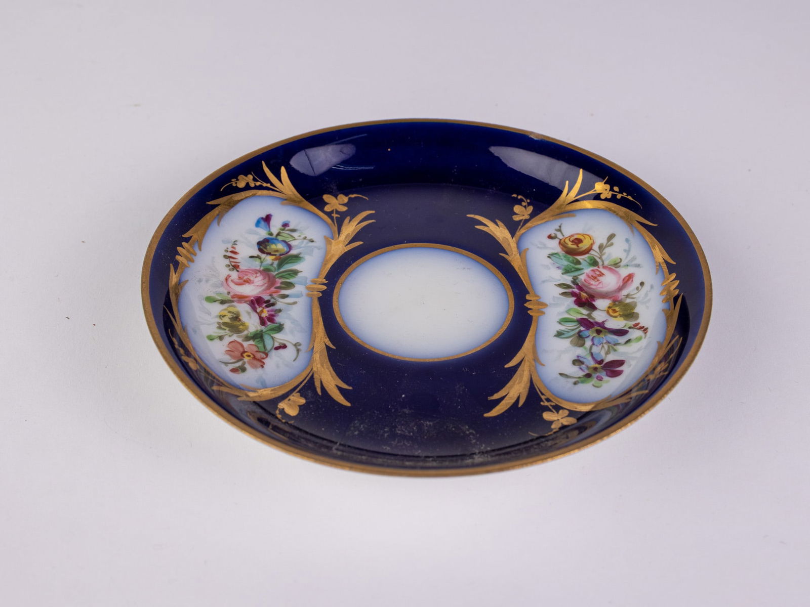 Château Des Tuileries, Sèvres Cobalt Porcelain Saucer: Porcelain cobalt saucer decorated with gold toned and floral motifs, approximately 5" in diameter, marked Chateau des Tuileries, Sèvres on the bottom.Size5" diameterLiteratureBrooks Auction
