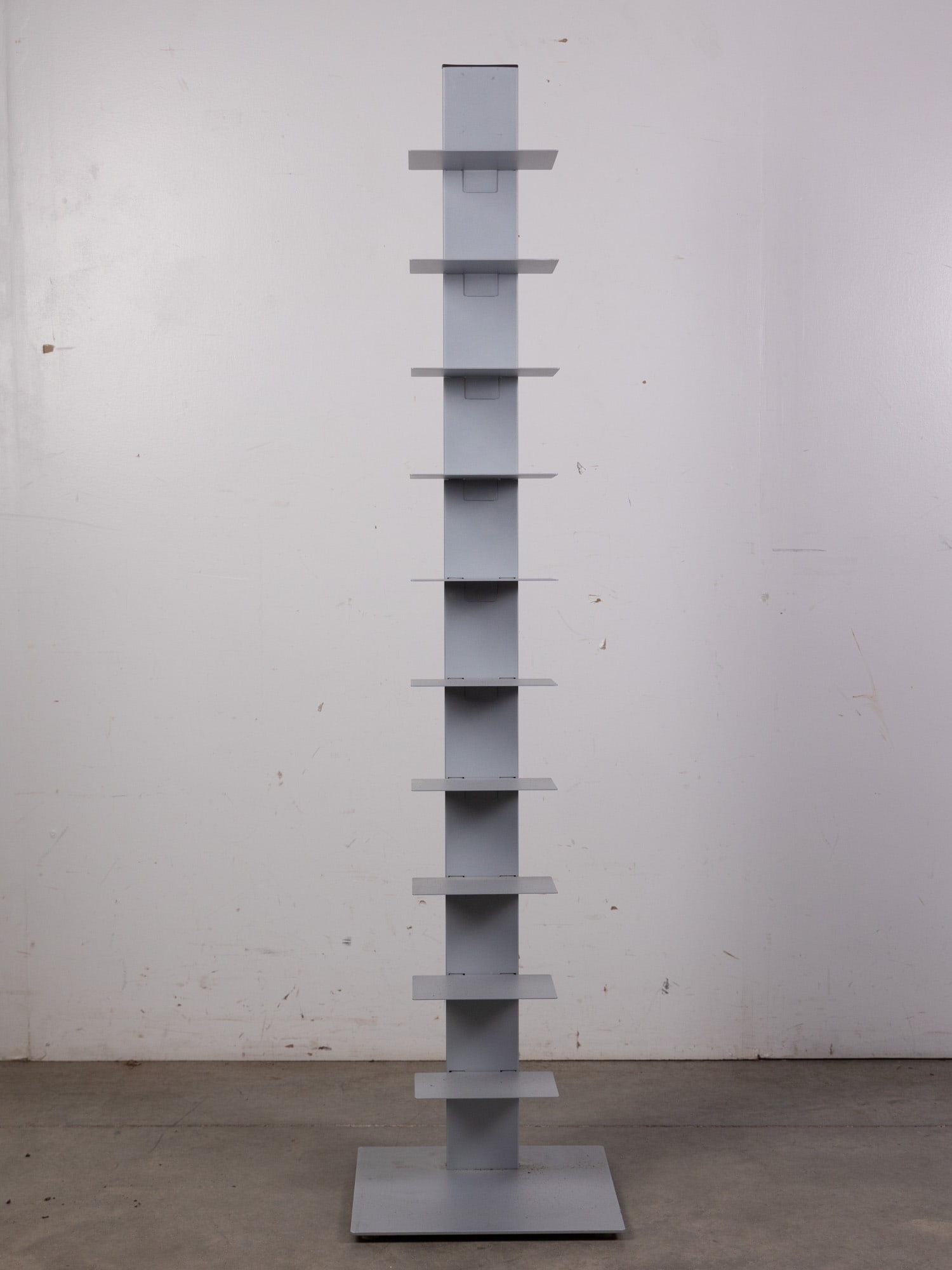After Bruno Rainaldi | Italian Modern "Sapiens" Book Shelf: In the style of Ptolomeo Bookcase or the Sapiens, a "floating" book stand with cantilevered metal shelves tucking into a 6' stand. In a grey finish.Size59.5" x 14" x 14"LiteratureBrooks Auction