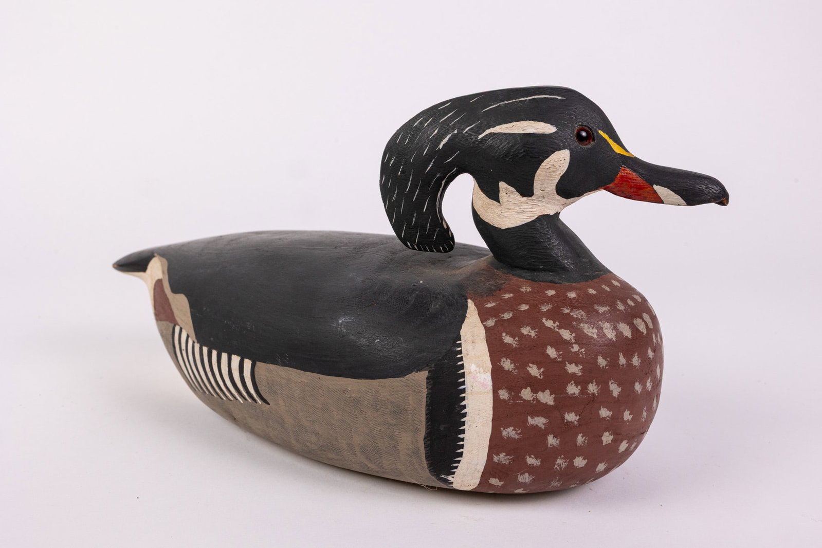 Garland Gaskins (1911-2010) | Wood Duck Drake Decoy: Carved by John Garland Gaskins of Wallops Island, VA, this wood duck decoy features hand painted detail and glass eyes. Signed on the bottom and dated 1971. Size 6" x 6" x 12" Literature Brooks Auctio