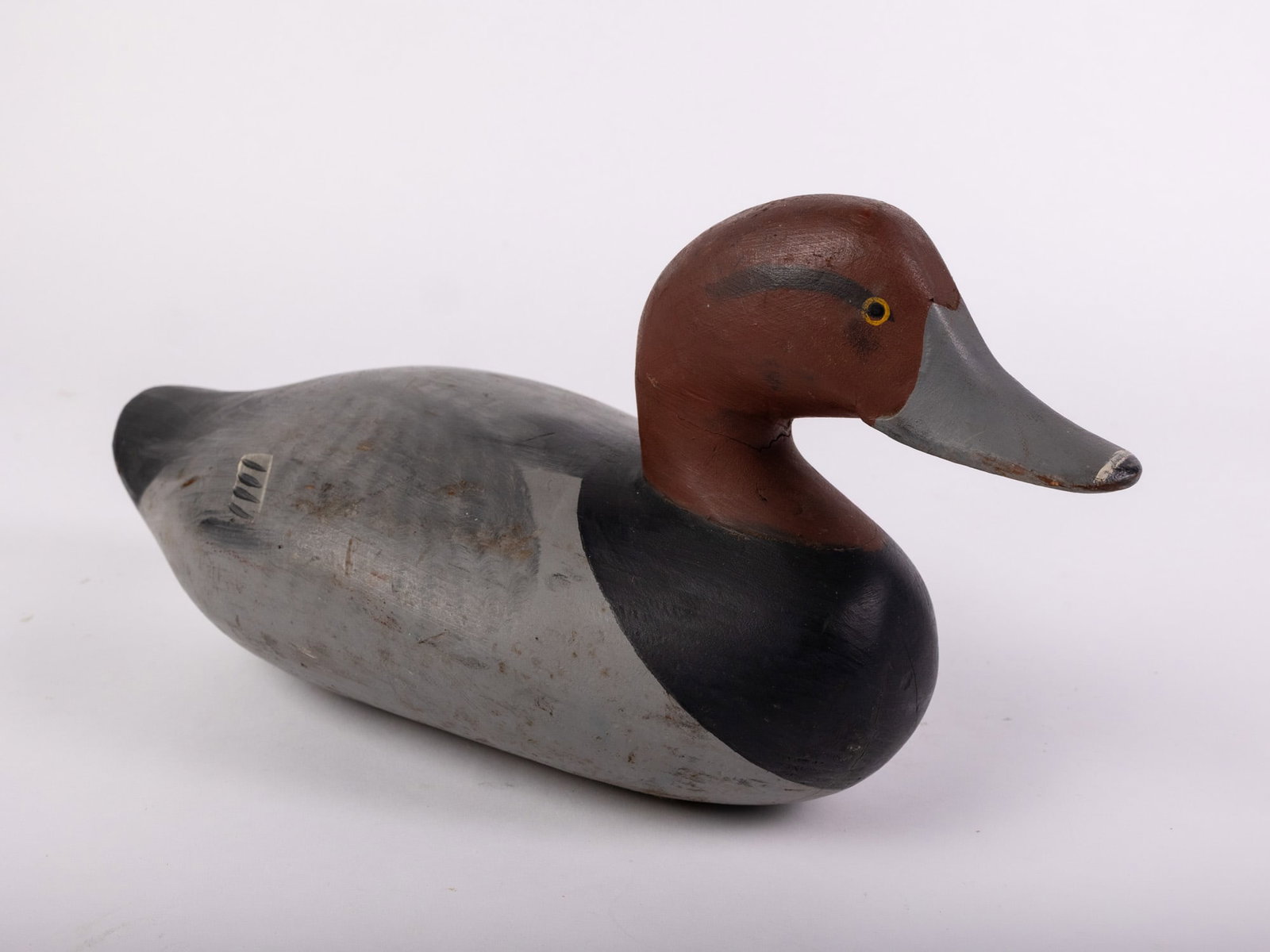 Vintage Redhead Drake Decoy: There is a branding mark on the base, possibly "E" or "rn". Hand painted and carved from wood. Some signs of wear/age in the paint. Size 7" x 7" x 14" Literature Brooks Auction – Online Auction