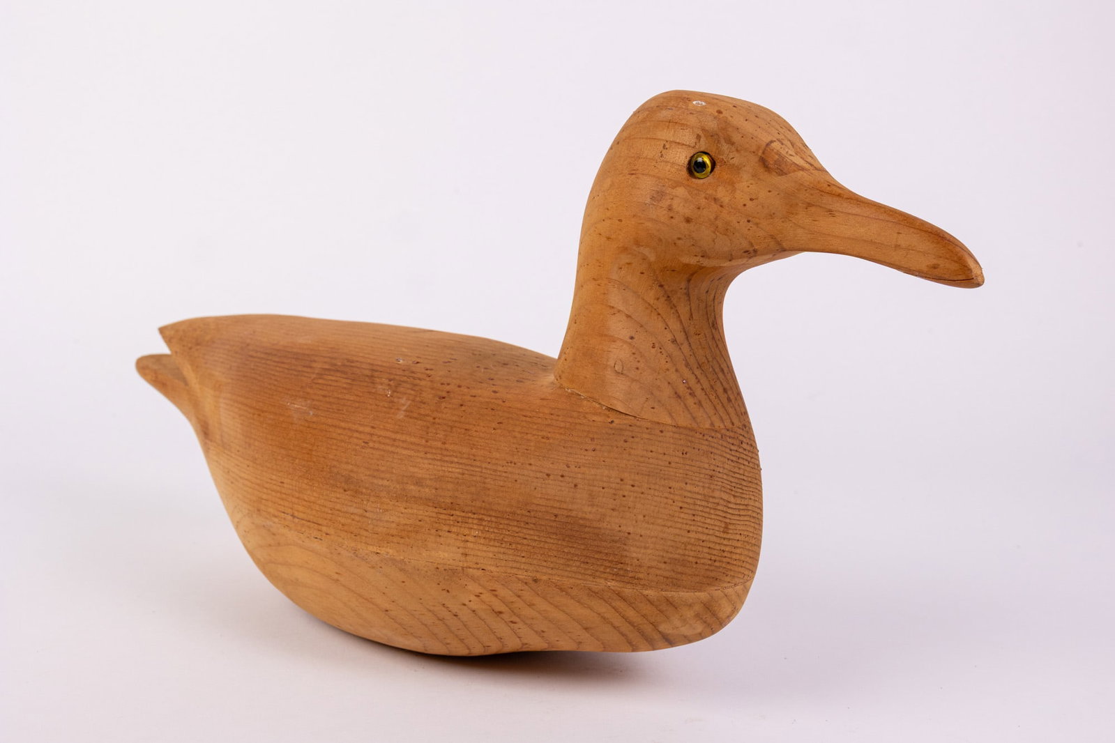 Vintage Hand Carved Duck Decoy w/ Blonde Wood Finish: Crafted from solid wood, with a smooth natural blonde finish & inset glass eyes. Size 7" x 4" x 16" Literature Brooks Auction – Online Auction Terms & Conditions Contact: (856) 694-2960 | info@