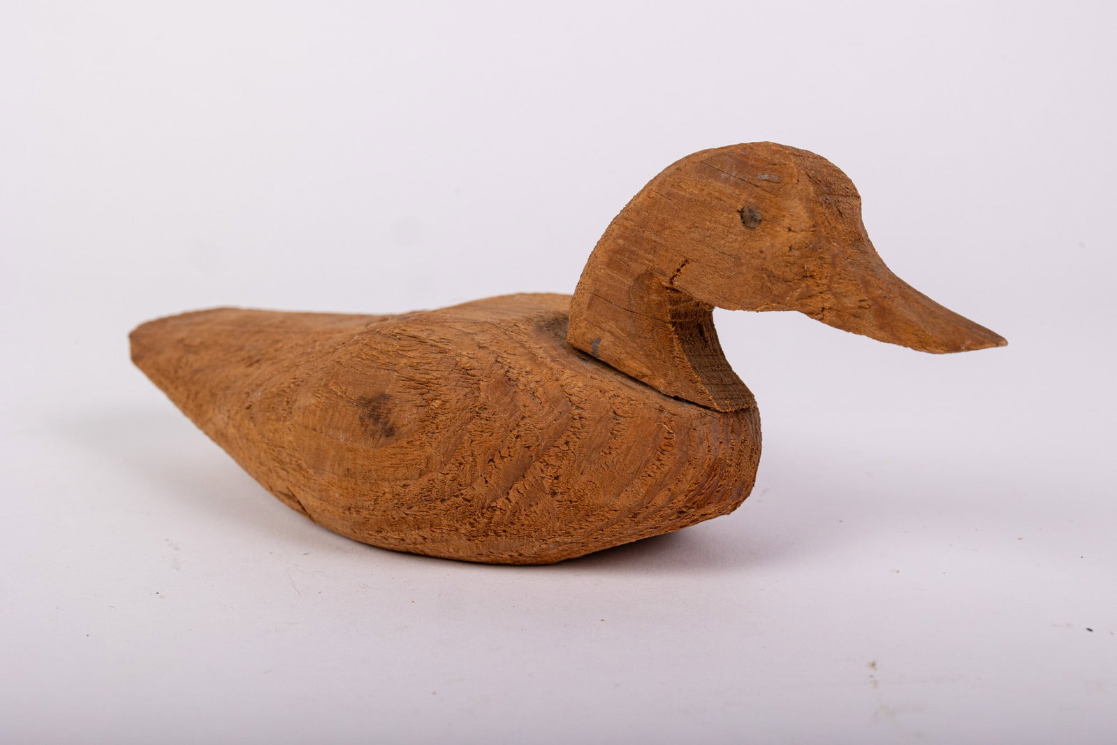 Vintage Hand Carved Duck Decoy w/ Natural Wood Finish: Crafted from solid wood, with a rough rustic finish. Size 5" x 4" x 12" Literature Brooks Auction – Online Auction Terms & Conditions Contact: (856) 694-2960 | info@brooks.auction READ BEFORE