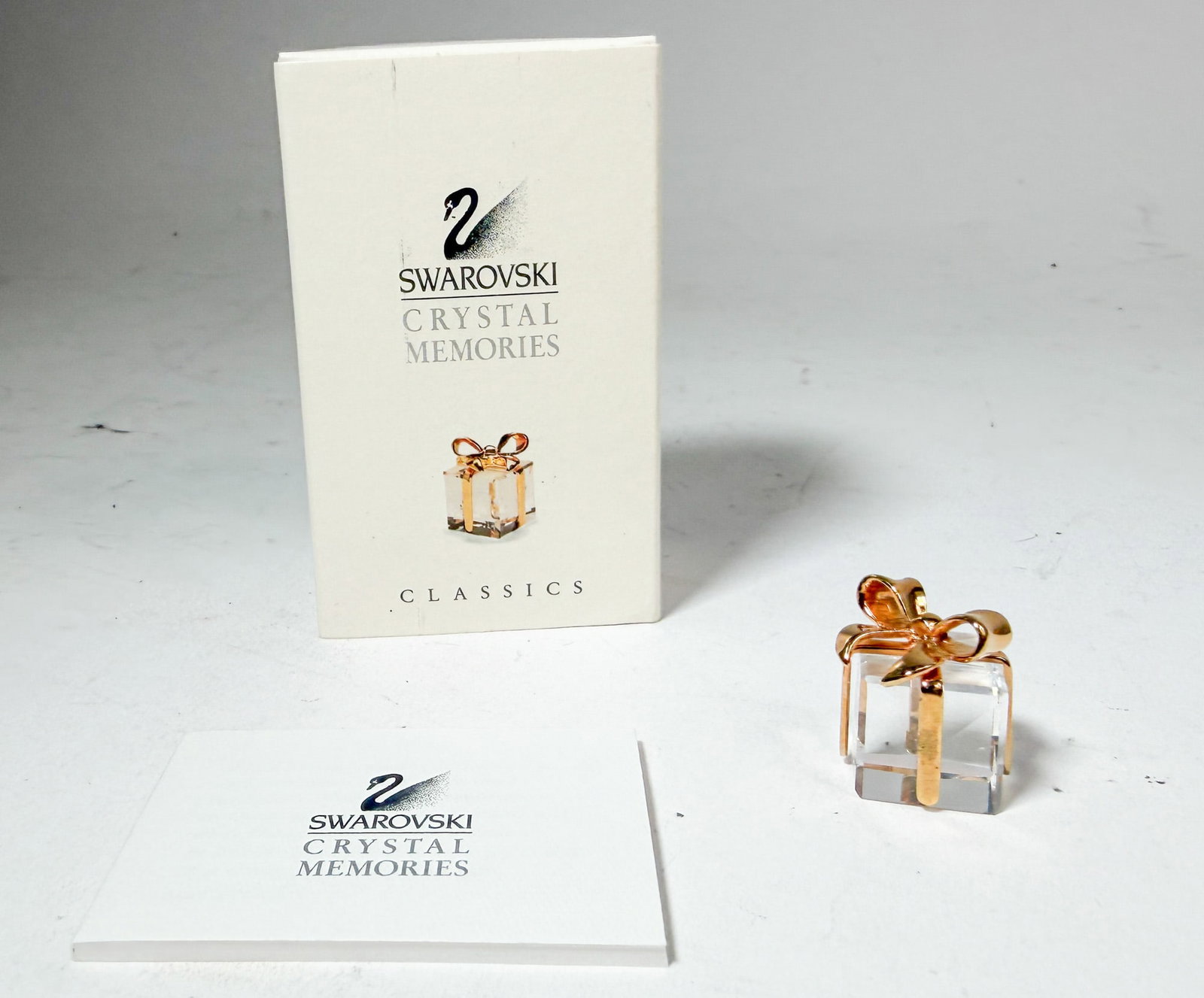 Swarovski Crystal Memories Mini Gift Box IOB: Swarovski Crystal Memories Mini Gift Box with golden bow IOB Size 1" H Literature Brooks Auction – Online Auction Terms & Conditions Contact: (856) 694-2960 | info@brooks.auction READ BEFORE