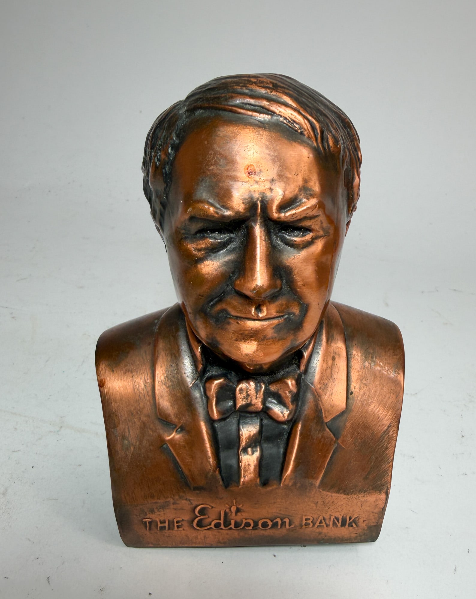 The Edison Bank Copper Toned Still Bank: The Edison Bank Copper Toned Still Bank, includes key! Size 6" H Literature Brooks Auction – Online Auction Terms & Conditions Contact: (856) 694-2960 | info@brooks.auction READ BEFORE YOU BID: