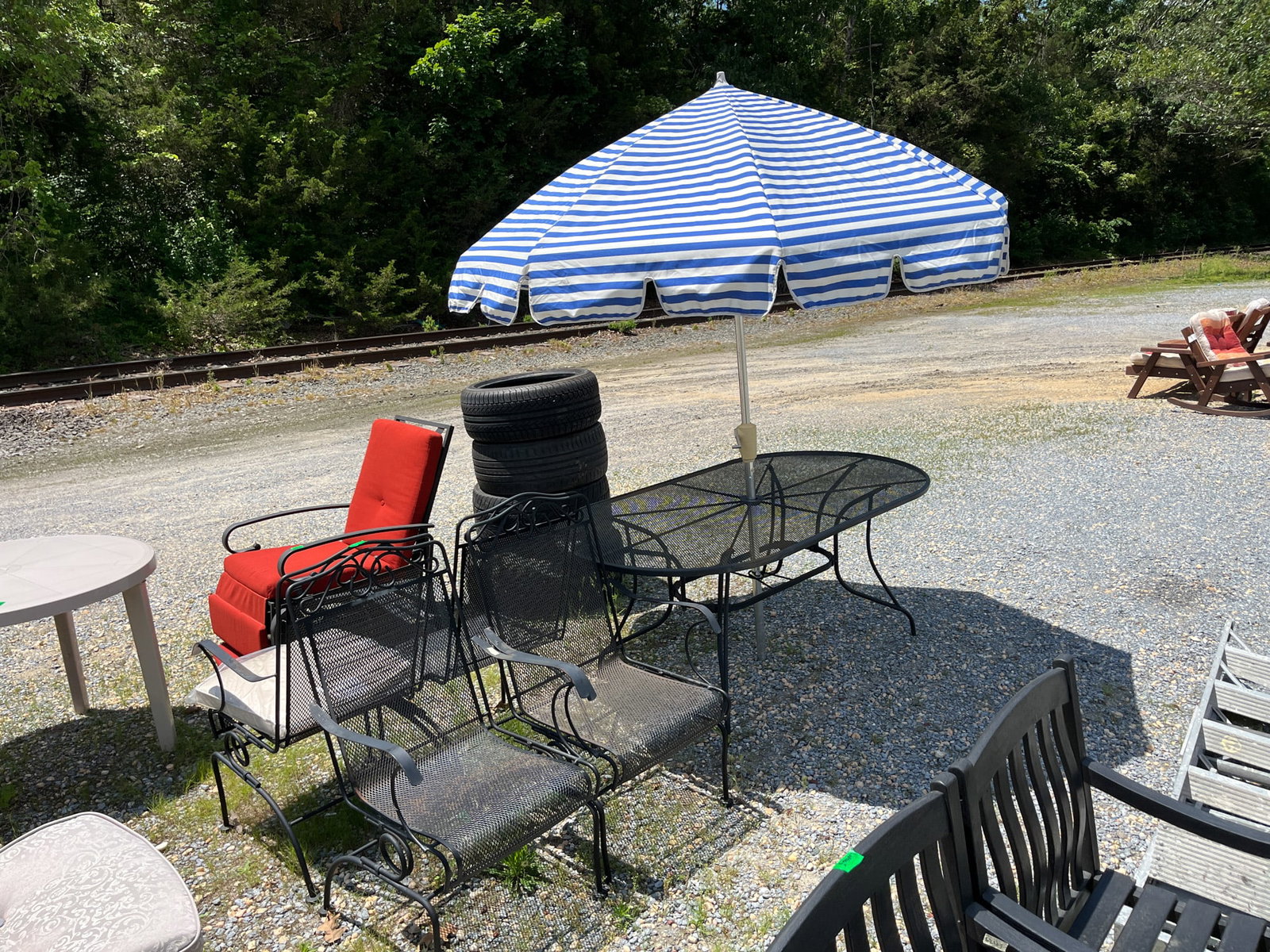 Five Piece Mesh Wrought Iron Outdoor Set with Umbrella: Large dining table with four chairs and stripe patterned umbrella Literature Brooks Auction – Online Auction Terms & Conditions Contact: (856) 694-2960 | info@brooks.auction READ BEFORE YOU