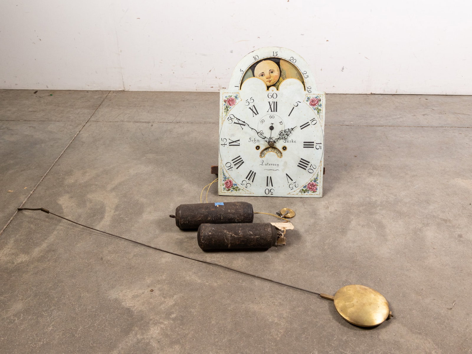 John Parke, Paterson, New Jersey Early 19th Century Clock Movement: Early 19th century clock movement by Paterson, New Jersey clock maker, John Parke. White painted face with painted roman numerals, featuring gold toned and floral detail work, with a rotating day to