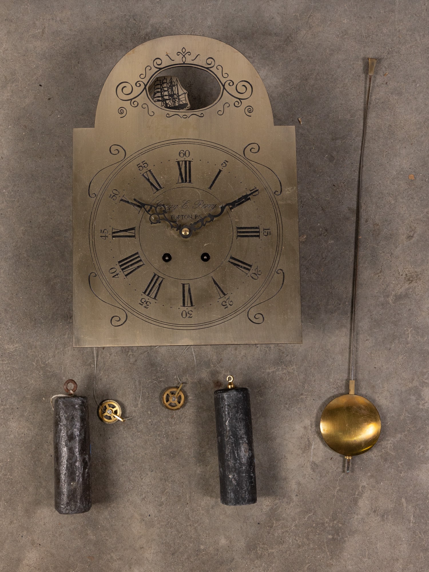Gregg E. Perry Vintage Brass Clock Movement: Vintage brass clock movement signed Gregg E. Perry of Topton, PA. Etched Roman numerals and swirling design with rocking tall ship figure. Includes weights and pendulum. Size 15" x 10" Literature
