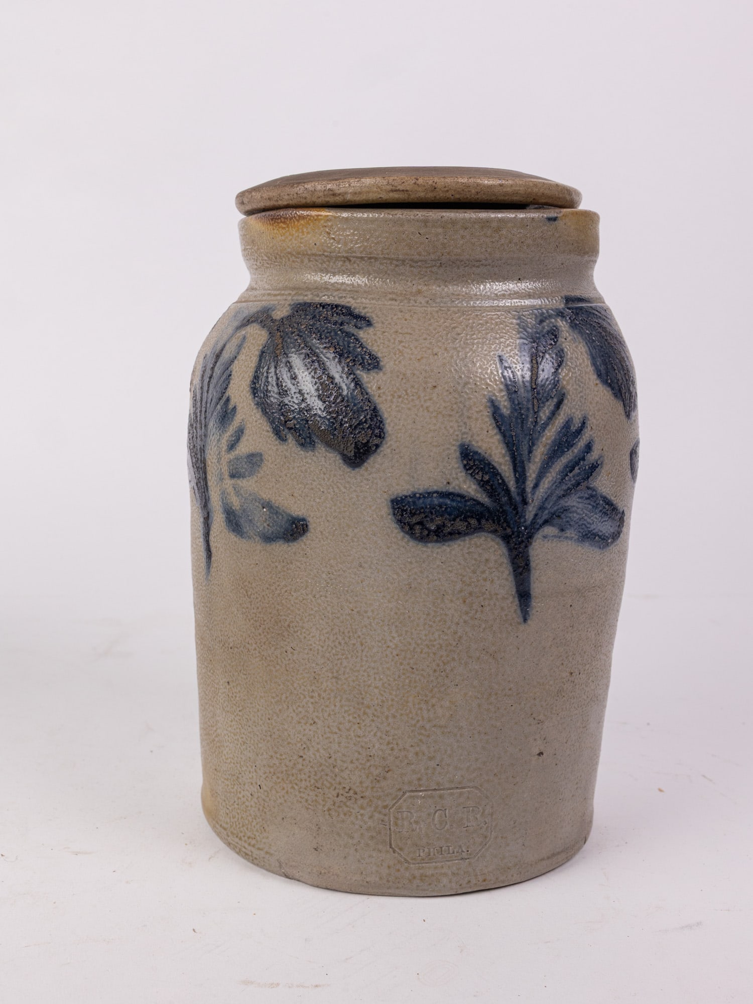 Richard C. Remmey Cobalt Decorated Salt Glazed Stoneware Crock with Lid: Salt glazed 9" tall crock with repeated floral cobalt pattern and lid. Stamped "R.C.R., Phila.", referring to Philadelphia stoneware manufacturer Richard C. Remmey. Size 9" H Literature Brooks