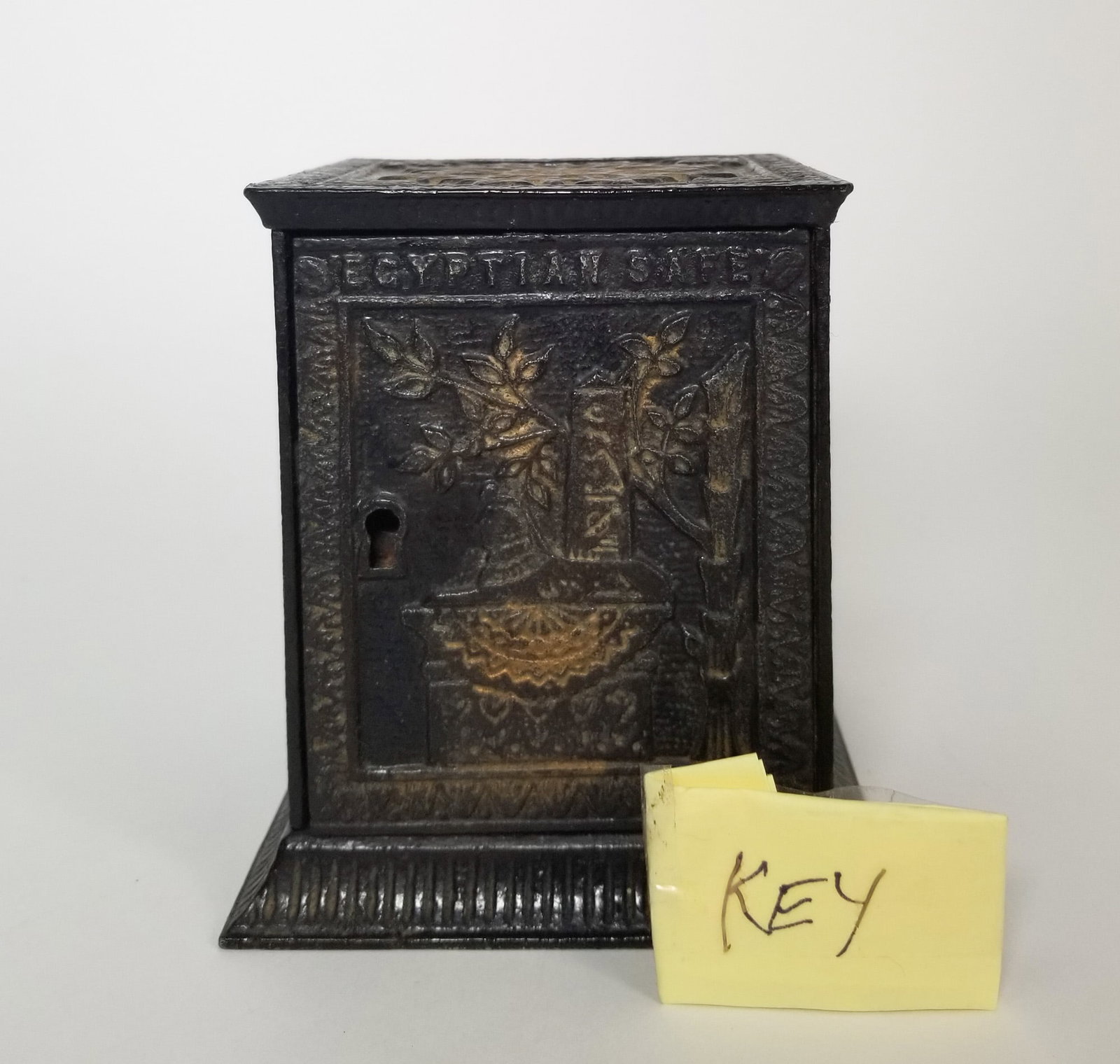 Antique "Egyptian Safe" Cast Iron Bank: Includes key. Damage to back base. Size 5" H Literature Brooks Auction – Online Auction Terms & Conditions Contact: (856) 694-2960 | info@brooks.auction READ BEFORE YOU BID: We want you to feel