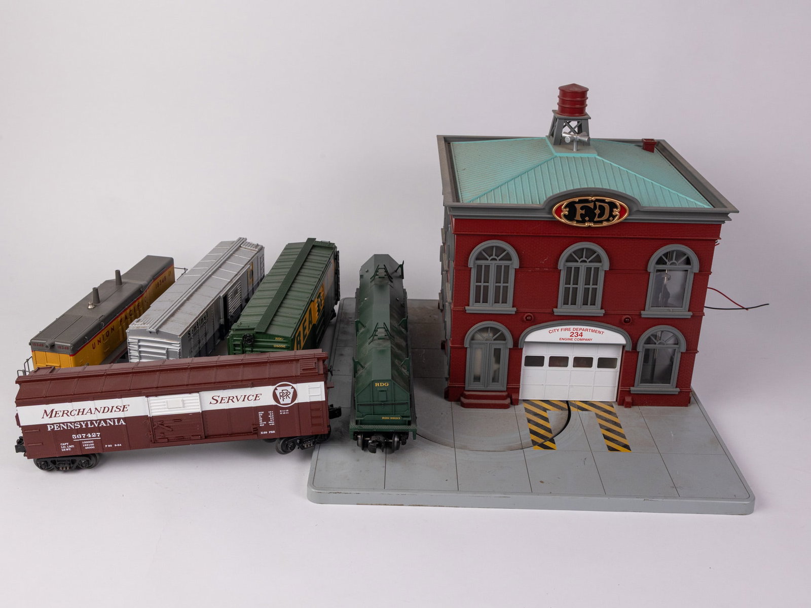 Assortment of Trains ft. MTH RailKing Operating Firehouse: MTH RailKing Operating Firehouse - MTH Premier O Scale Reading Coil Car - MTH Reading O Scale Premier Box Car - and more! Size 7" x 12" x 12" Literature Brooks Auction – Online Auction Terms & C