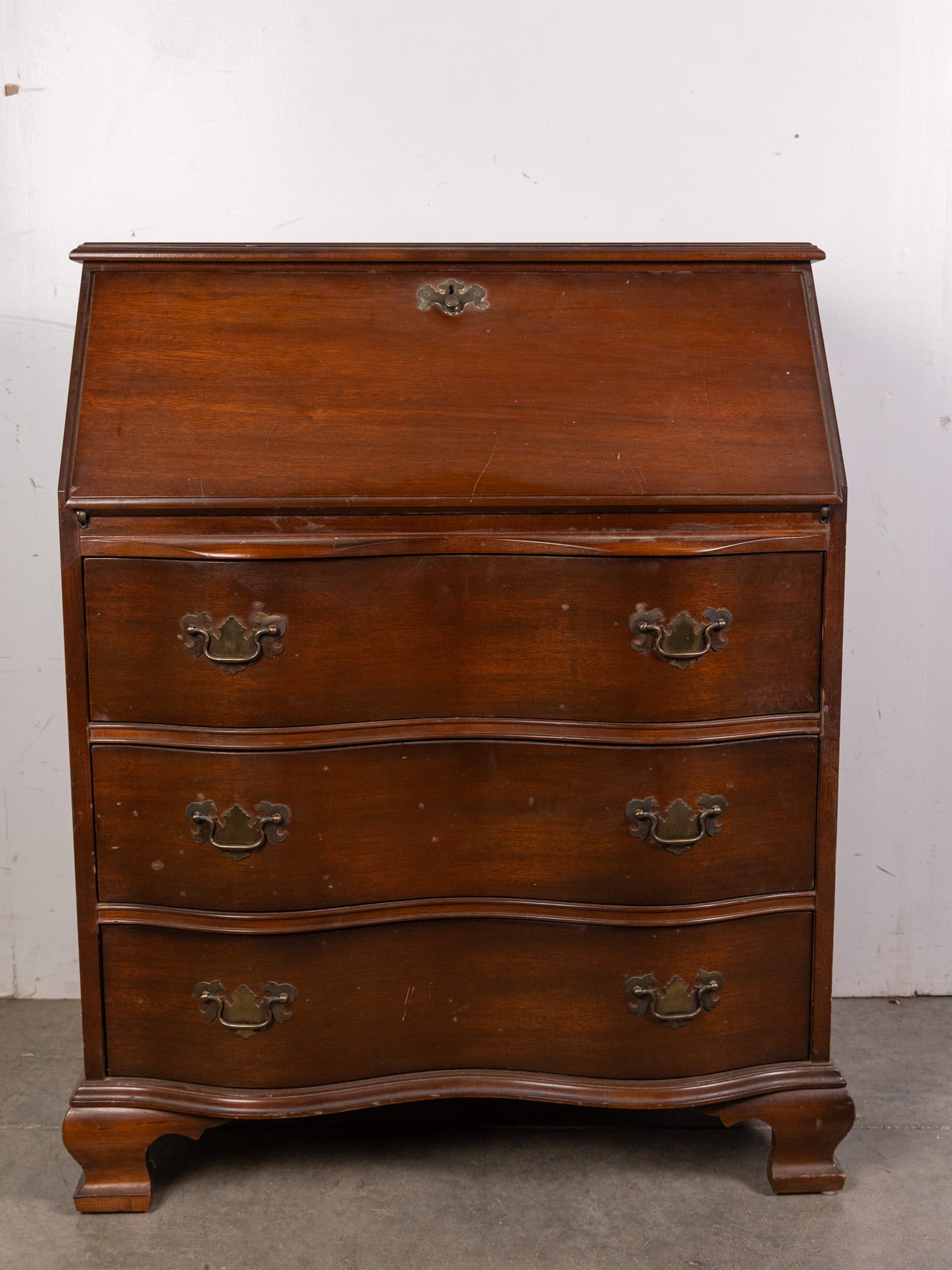 Vintage Serpentine Writing Desk: Includes key. Size 38" x 30" x 16" Literature Brooks Auction – Online Auction Terms & Conditions Contact: (856) 694-2960 | info@brooks.auction READ BEFORE YOU BID: We want you to feel confident