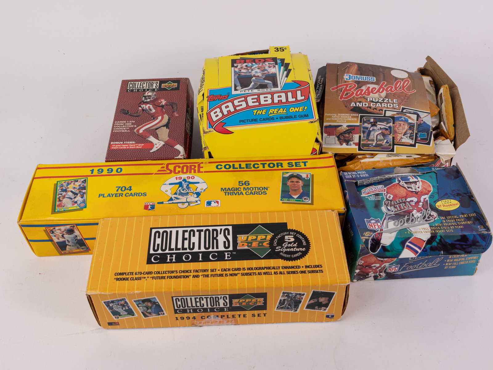 Assortment of Sports Cards ft. Topps MLB: The Real One! Box Set: This assortment of sports cards features various card set boxes such as unopened Donruss Baseball Puzzle & Cards packs, unopened Topps MLB: The Real One! card packs, and other assorted cards from boxe