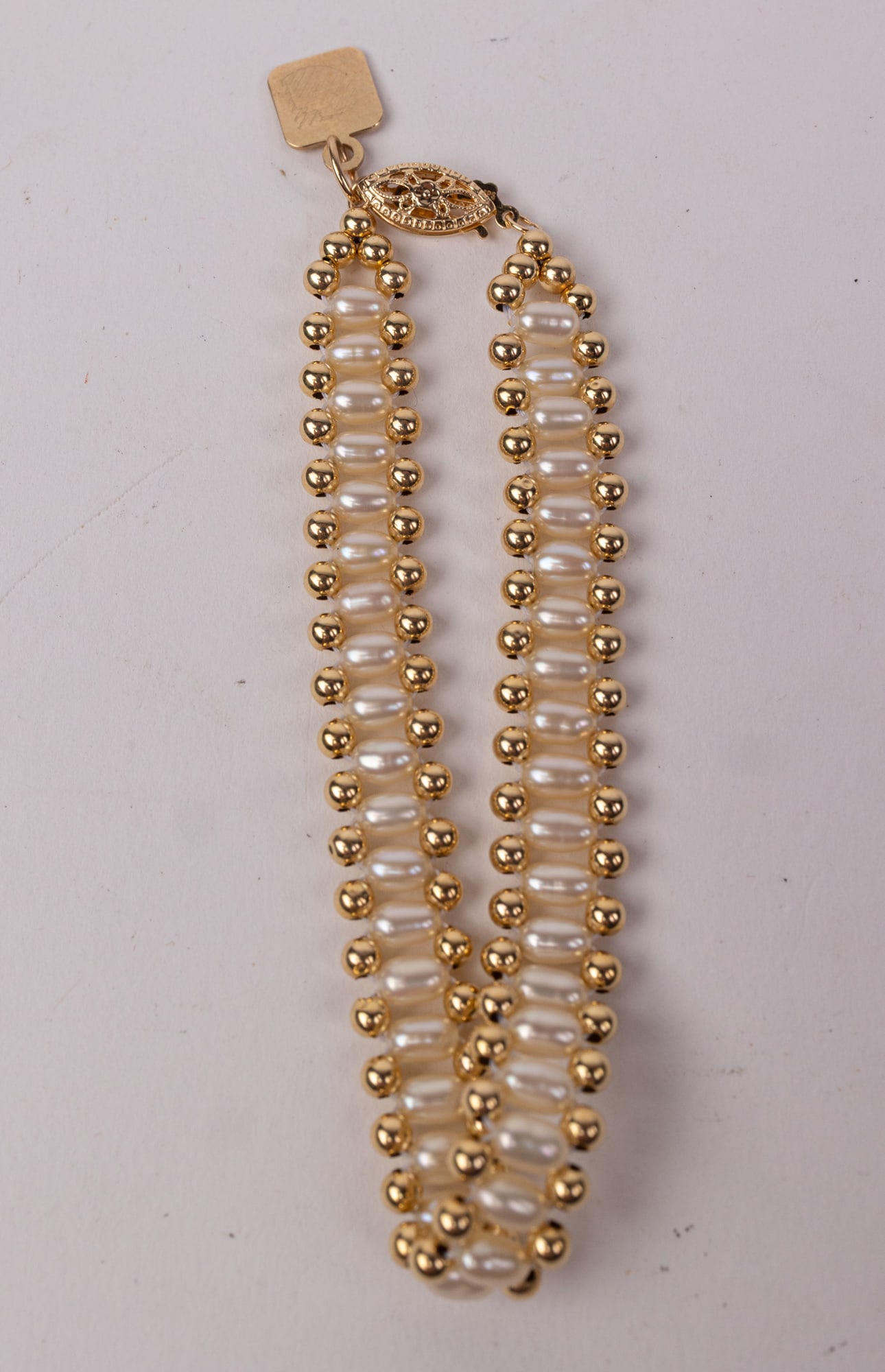 14KY Gold Pearl Bracelet with 10KY Charm: Marked "14K IPS" on the clasp and "Tharpe 10KT" on the charm, Total weight 5.1 grams Literature Brooks Auction – Online Auction Terms & Conditions Contact: (856) 694-2960 | info@brooks.auction