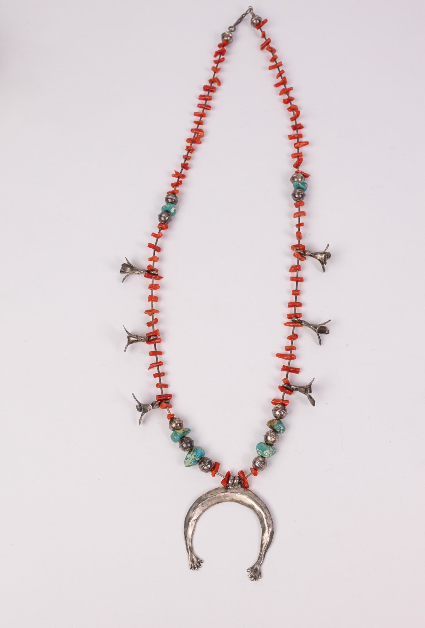 Vintage Silver Navajo-Style Squash Blossom Necklace with Naja Pendant: Constructed of red coral branches, turquoise and silver. Total weight is 43 grams Literature Brooks Auction – Online Auction Terms & Conditions Contact: (856) 694-2960 | info@brooks.auction