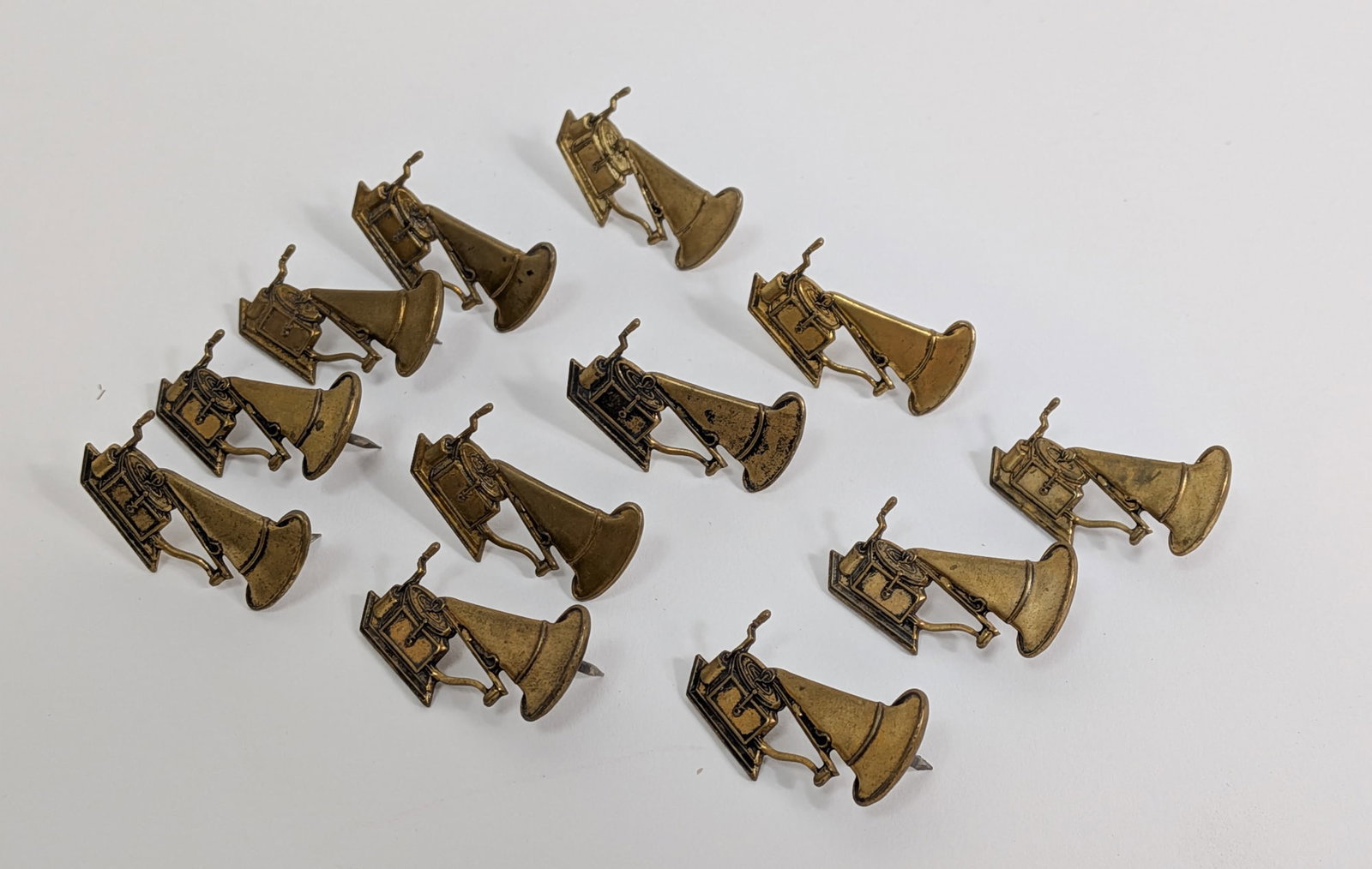(12) Gold-Toned Gramophone/Phonograph Pins: (12) Gold-Toned Gramophone/Phonograph Pins Literature Brooks Auction – Online Auction Terms & Conditions Contact: (856) 694-2960 | info@brooks.auction READ BEFORE YOU BID: We want you to feel