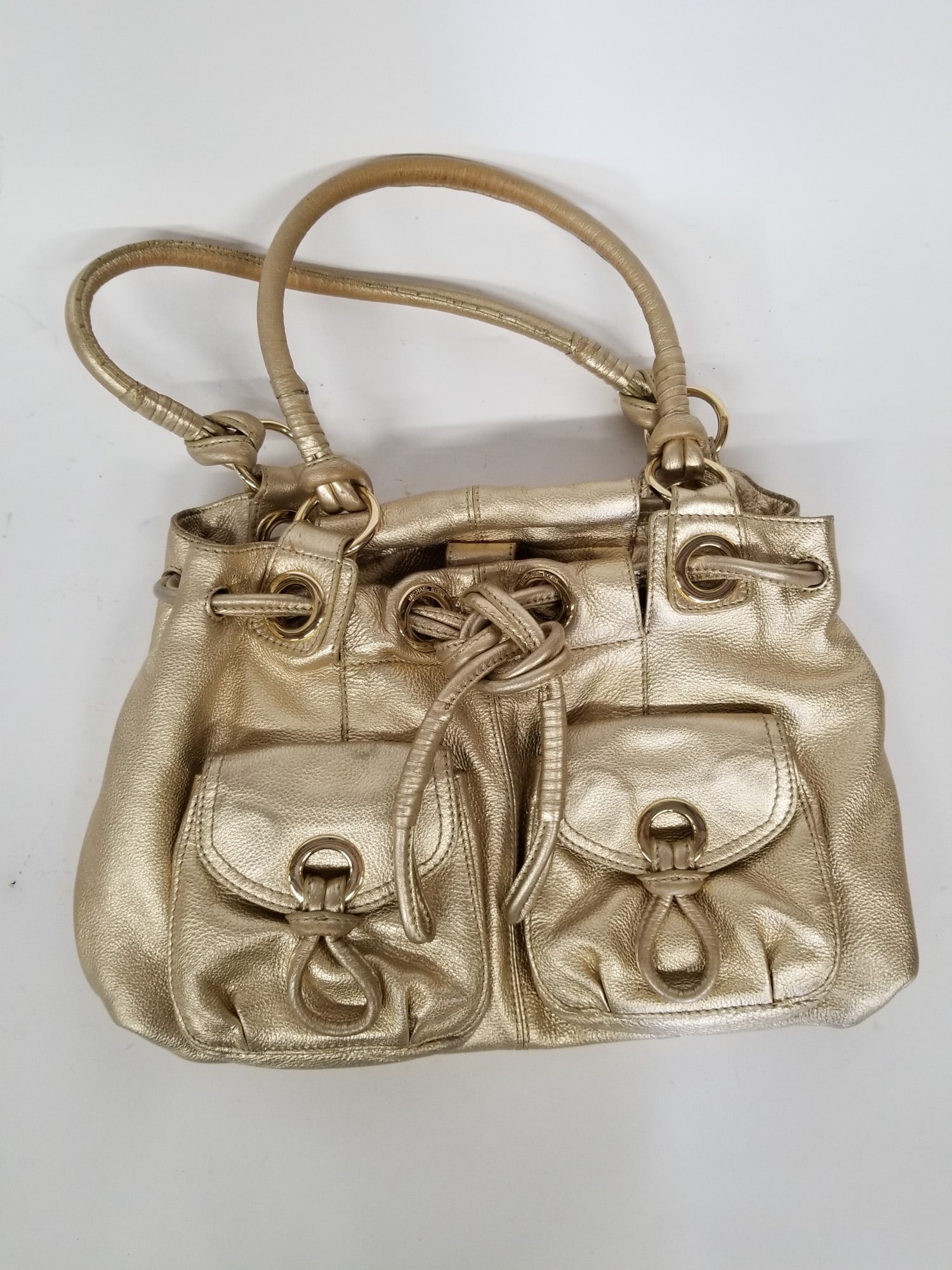 Michael Kors Metallic Gold Leather Handbag: Metallic gold leather handbag by Michael Kors. Size 8" x 16" x 5" Literature Brooks Auction – Online Auction Terms & Conditions