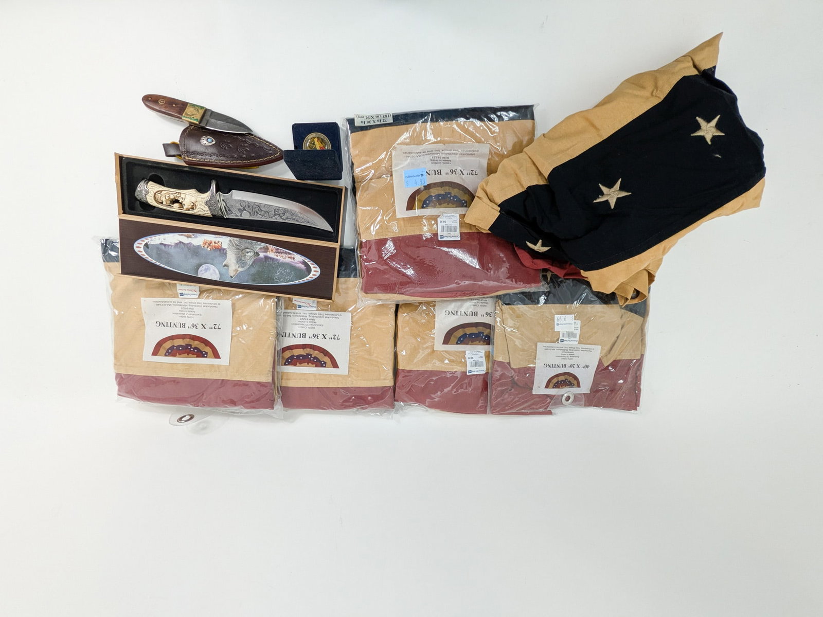 Assorted American Heritage Lot: This assortment include six (6) bunting flags, a wolf-etched display knife, a small fixed blade with a Cutlery Salvation sheath, and an Operation Enduring Freedom challenge coin. Size 7" x 12" x 12" L