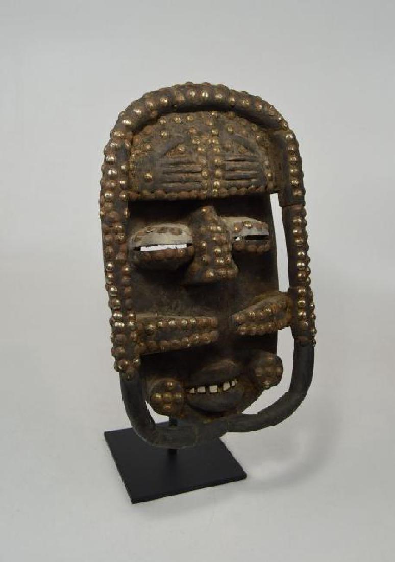 Vintage Bete Mask: Carved wooden mask from the Bete peoples of the central Ivory Coast, West Africa. The mask has stylized horns and has been heavily accented with metal tacks, inset teeth and two Hand motifs on the for
